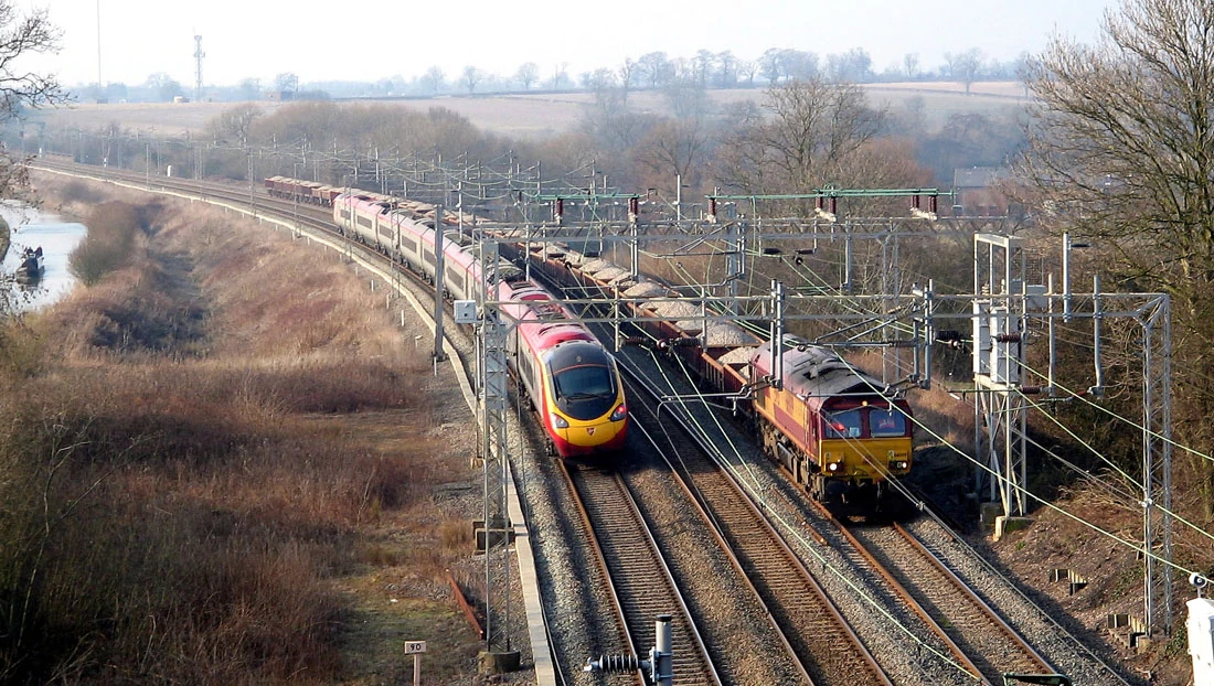 Obrázek zprivatizovaných železnic. Pendolino dopravce Virgin Trains míjí nákladní vlak společnosti EWS na trati West Coast Main Line v hrabství Warwickshire. Autor: G-MAN – Vlastní dílo, CC BY-SA 3.0, wikipedia